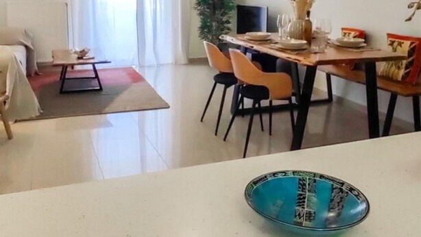 A modern dining area with a wooden table set for four, surrounded by chairs. - Filoxenia in the Centre of Kalamata (Kalamata)