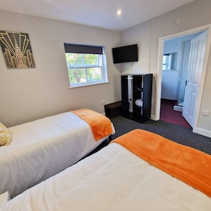 A hotel room with two beds, a TV, a wardrobe, and a window. - Stay Norwich Apartments Riverside House Apart-4 (Norwich)