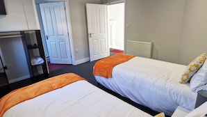 A hotel room with two beds, a desk, and a radiator. - Stay Norwich Apartments Riverside House Apart-4 (Norwich)