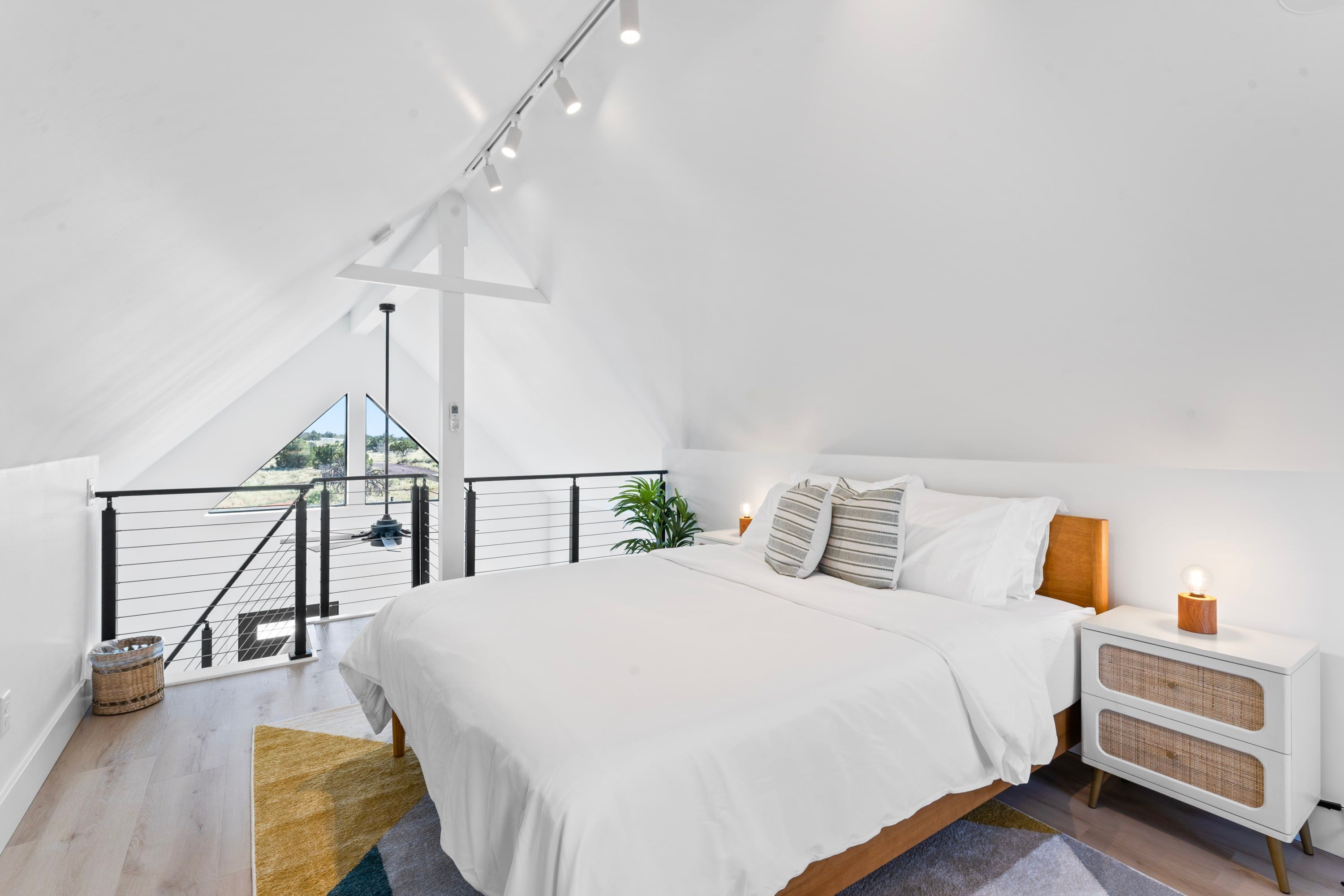 Slaapkamer met een groot bed, nachtkastje, lamp, plant en uitzicht op het groen via een balkon.