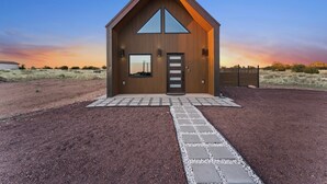 Un bâtiment moderne en bois, doté d’un toit triangulaire, d’une grande fenêtre et d’une porte.