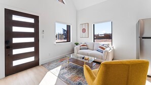 Un salon moderne avec un canapé, un fauteuil jaune et une table basse en verre.