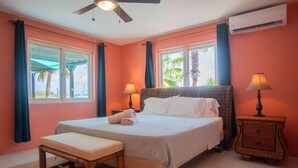 A bedroom with a bed, bedside tables, a bench, and a ceiling fan. - Beautiful Luxury Home in Seroe Colorado (San Nicolas Zuid)