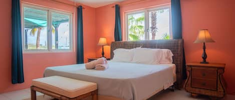 A bedroom with a bed, bedside tables, a bench, and a ceiling fan.