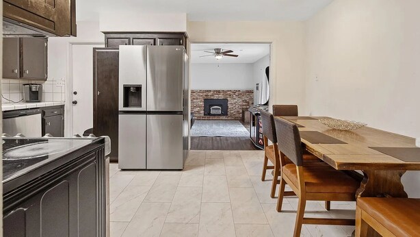 Una cocina moderna con un refrigerador de acero inoxidable, gabinetes de madera y un comedor con mesa y sillas de madera.