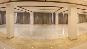 Un salón amplio con suelos de mármol, pilares imponentes y cortinas en las ventanas.