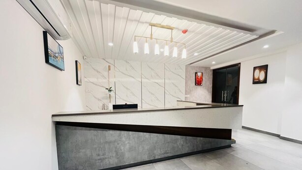Un moderno mostrador de recepción con pared de mármol, una separación de vidrio e iluminación empotrada en el techo.