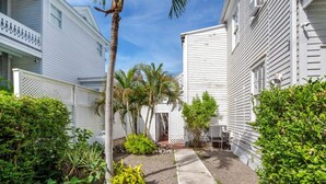 A narrow pathway leading to a gated entrance surrounded by lush greenery and palm trees. - Banana Split by Brightwild Pool Grill (Key West)