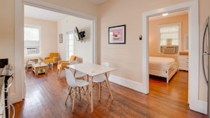 A modern living room with a white table and chairs, a sofa, and a bed in the adjacent room. - Banana Split by Brightwild Pool Grill (Key West)