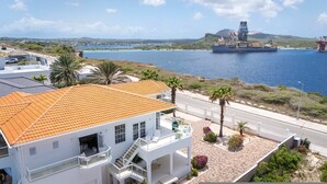 A coastal property with a white building featuring a red-tiled roof, a balcony, and a view of the sea. - Artiko Luxury Suites - Jan Thiel (Jan Thiel)