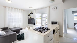 A modern kitchen with a gas stove, microwave, and a dining area with a white table and chairs. - Artiko Luxury Suites - Jan Thiel (Jan Thiel)