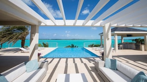 A pool area with a view of the ocean, lounge chairs, and a covered seating area. - 5 BR Waterfront Villa On Chalk Sound Blue Water (Providenciales)