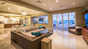 A spacious living area with a large sofa, a coffee table, and a view of the beach through the glass doors. - 5 BR Waterfront Villa On Chalk Sound Blue Water (Providenciales)