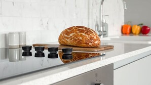 A kitchen with a loaf of bread on a cutting board, a sink, and a stove. - Bright Chelsea apt sun Terrace (London)