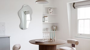 A modern dining area with a round table, two chairs, a pendant light, and a mirror on the wall. - Bright Chelsea apt sun Terrace (London)