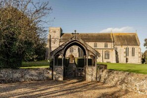 A historic stone building with a prominent arched entrance and a small tower. - Host Stay The Chapel in Thornham (Hunstanton)
