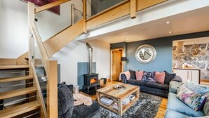 A modern living room with a staircase, a fireplace, a sofa, and a coffee table. - Host Stay The Chapel in Thornham (Hunstanton)