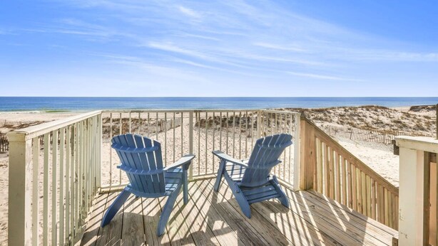 A wooden deck with two Adirondack chairs overlooking a beach. - Sunrise Village 215- 2BR 1BA Gulf Front Sleep 6 (Gulf Shores)