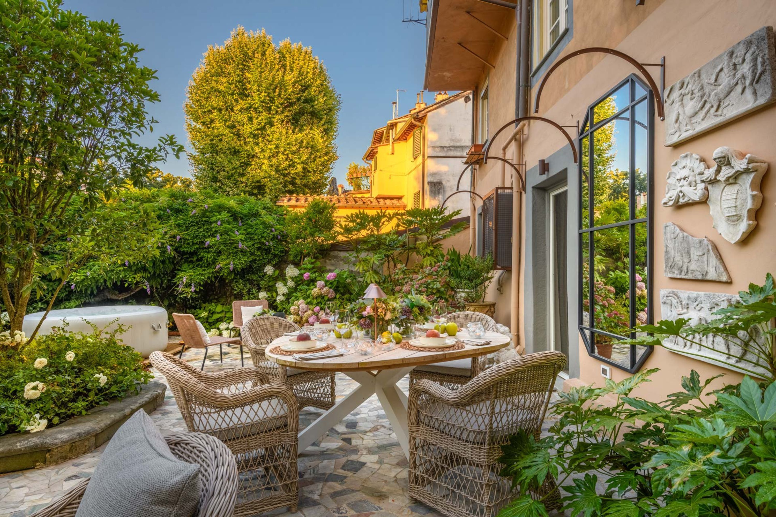 Una terrazza con mobili in vimini, un tavolo rotondo e una pianta in vaso.