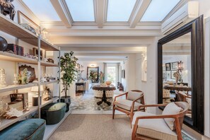 A spacious living room with a high ceiling, a large mirror, and a central round table.