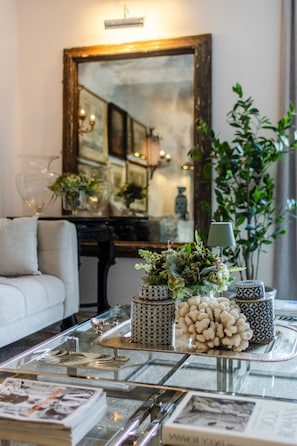 A living room with a glass coffee table, decorative vases, and a mirror on the wall.