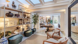 A spacious living room with a high ceiling, skylights, a large potted plant, and a seating area with a sofa and chairs. - The Garden Lodge in Lucca (Lucca)