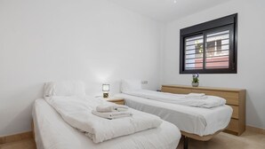 A clean, modern bedroom with two single beds, a bedside table with a lamp, a wooden dresser, and a window with blinds. - Cozy Getaway With Pool in Riviera del Sol - Ref 99 (Mijas)