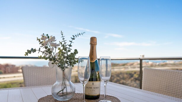 A bottle of Jaume Serra cava wine, two glasses, and a vase with flowers on a table with a view. - Cozy Getaway With Pool in Riviera del Sol - Ref 99 (Mijas)