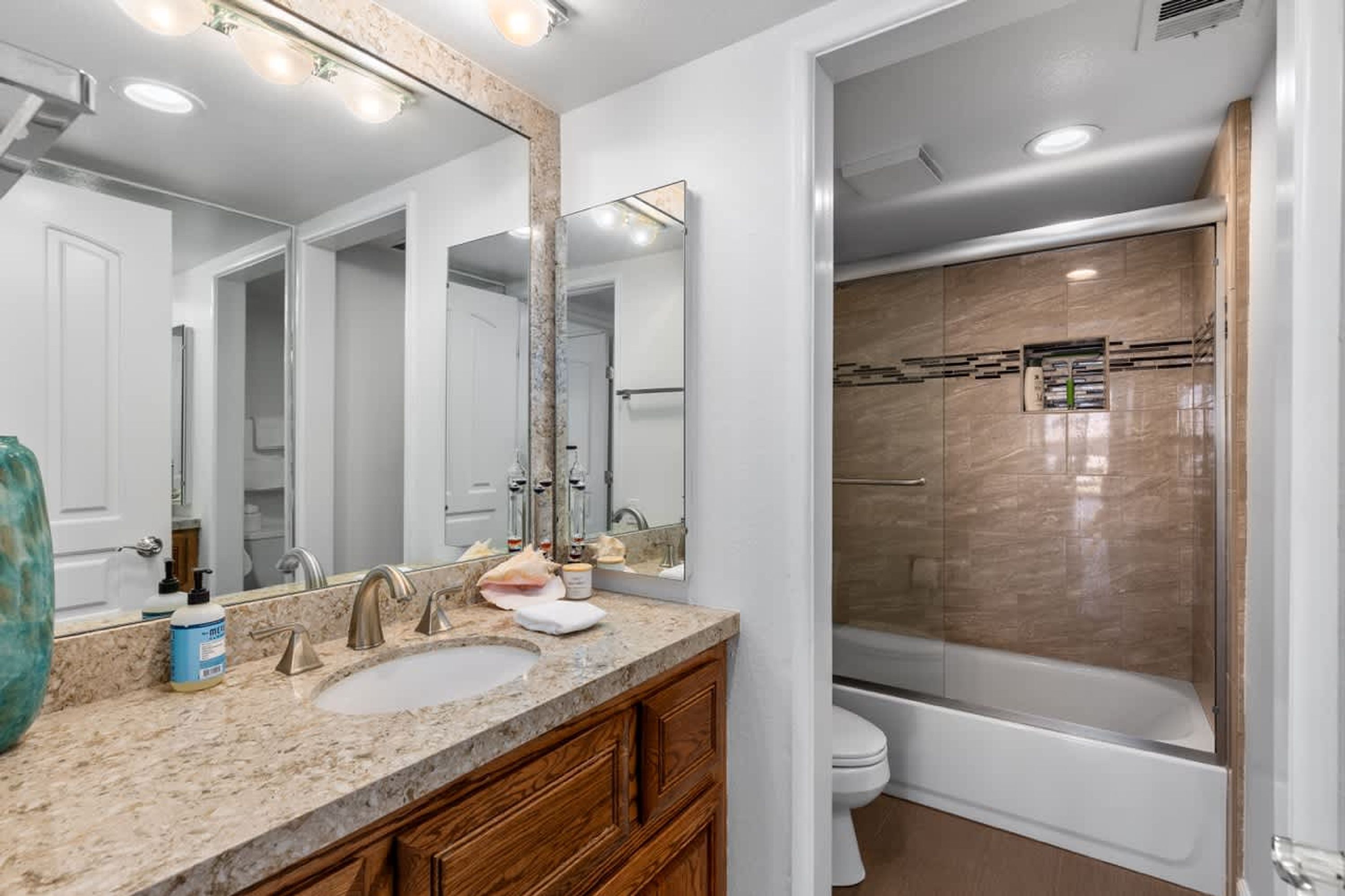 Un baño moderno con un espejo grande, un lavamanos y una zona de ducha.