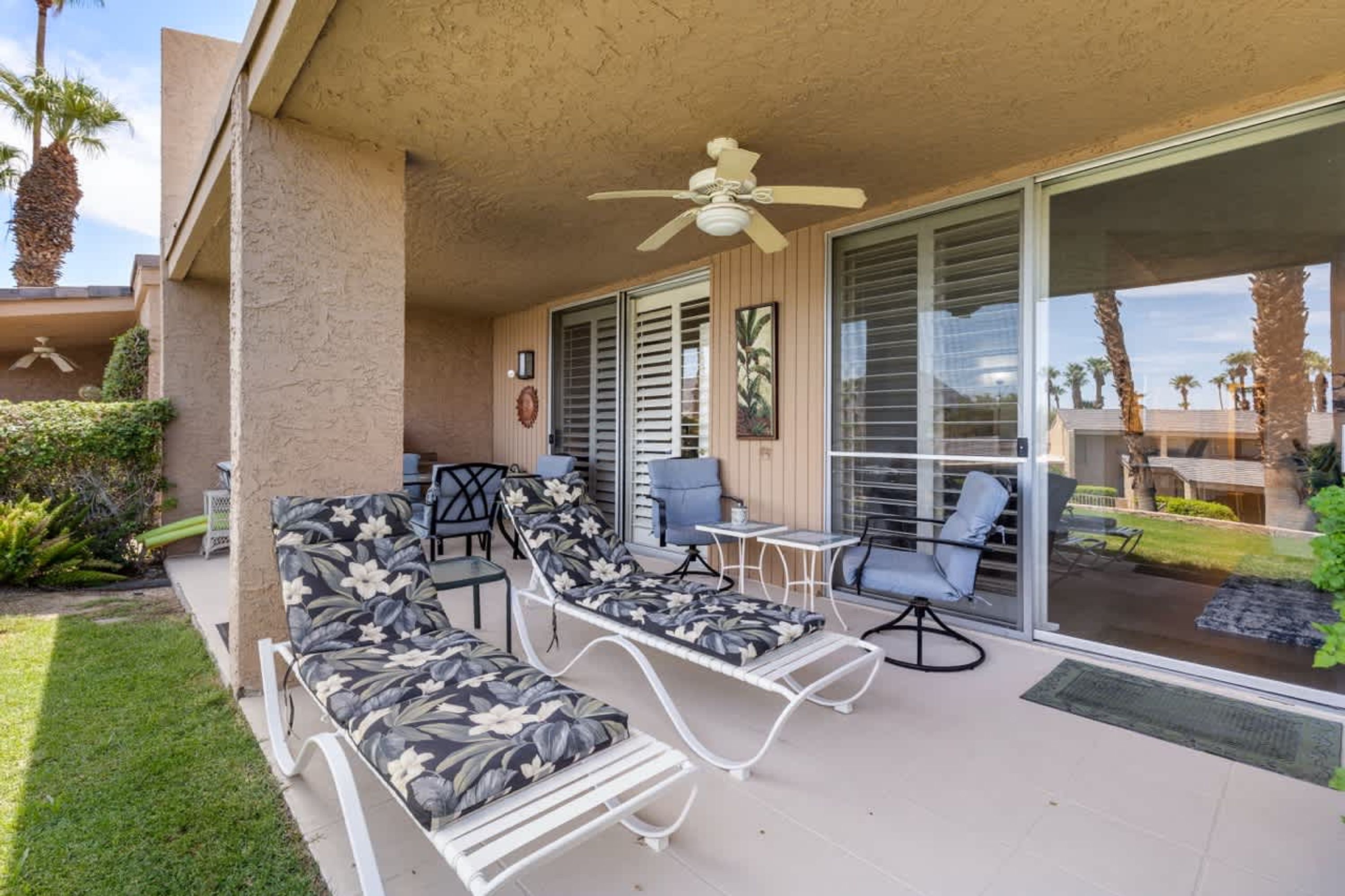 A covered outdoor area with a ceiling fan, a pool table, and lounge chairs.