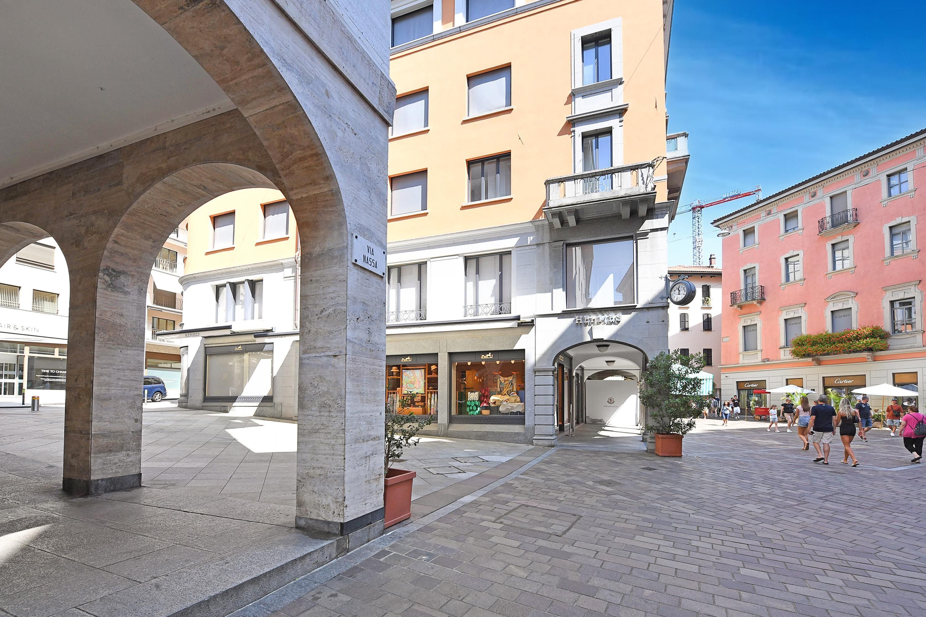 A public square with a café, a store, and a building with a clock.