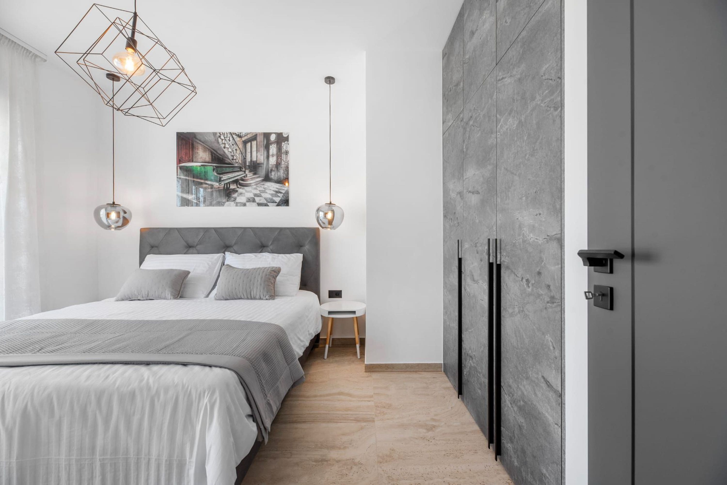 A modern bedroom with a bed, a side table, a wall-mounted picture, and a wardrobe.