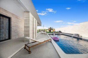 A modern outdoor pool area with a lounge chair, a swan-shaped water feature, and a clear blue sky. - Villa Jollie Zadarvillas (Benkovac)