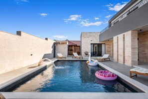A modern pool area with lounge chairs, a swan float, and a pink inflatable ring. - Villa Jollie Zadarvillas (Benkovac)