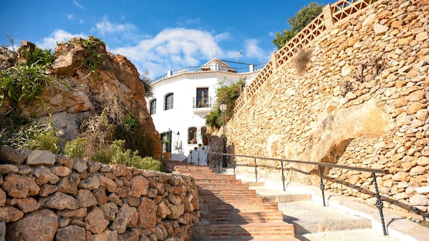 A stone staircase leading to a white building with a balcony, surrounded by rocky terrain and vegetation. - Casa La Era in Frigiliana (Frigiliana)