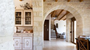 Un intérieur aux murs de pierre, agrémenté d’un escalier en bois, d’un coin repas et d’un meuble avec des portes en verre.
