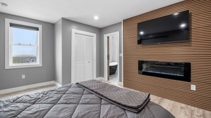 Ein Schlafzimmer mit einem Bett, einem Fernseher und einem Kamin.