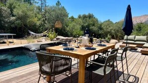 A wooden deck with a pool, outdoor furniture, and a dining table set for four. - Casa di Macchjerolu - 8 Pers (Sotta)