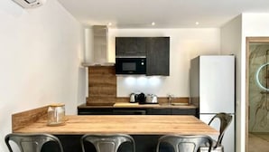A modern kitchen with a wooden island, black cabinets, and a white refrigerator. - Casa di Macchjerolu - 8 Pers (Sotta)