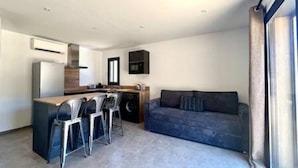A modern living room with a sofa and a dining area with bar stools. - Casa di Macchjerolu - 8 Pers (Sotta)