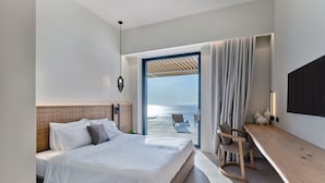 Habitación de hotel moderna con una cama grande, un escritorio y vista al mar.