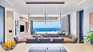 Una sala de estar moderna con comedor, un televisor de pantalla plana grande y vista al océano.