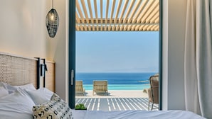 Un dormitorio con cama, vista al océano y un patio con sillas.