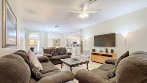 Uma sala de estar espaçosa com um amplo sofá, uma mesa de centro e uma TV de tela plana na parede.