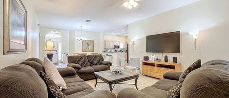 A living room with a sofa set, a coffee table, a TV, and a ceiling fan.
