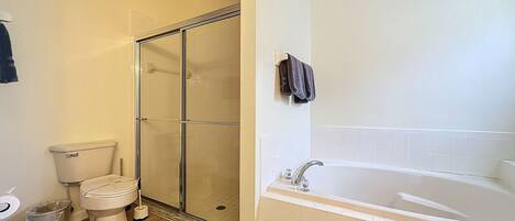 A bathroom with a toilet, a glass-enclosed shower, and a bathtub.