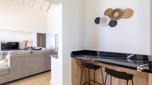 Eine moderne Küche mit schwarzem Arbeitsplatz, zwei Barhocker und einem Wanddekor.