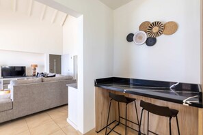 Eine moderne Küche mit schwarzem Arbeitsplatz, zwei Barhocker und einem Wanddekor.