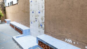 Una pared con azulejos, una puerta, escalones que conducen a una puerta y una pared con bajante.