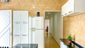 A kitchen with a granite countertop, white cabinets, and a refrigerator. - Tima Casa com Wifi pr Ximo a Praia em Itanha m SP (Itanhaém)
